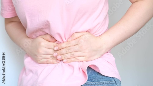Female hands squeeze the stomach on white background, the concept of abdominal pain. photo