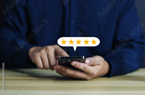 Icon on customer hand pressing on smartphone screen with golden five star feedback icon and awesome rating for best rating to review service business concept