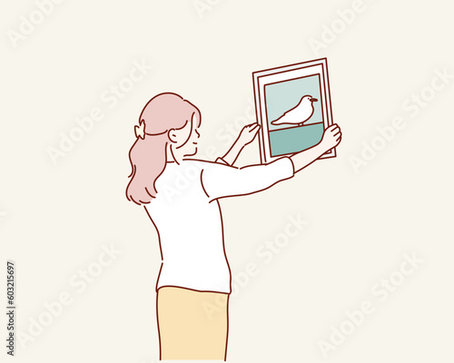 Woman hanging blank photo frame on white wall. Hand drawn style vector design illustrations.