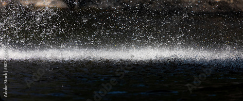 Stopped motion of splashing waterfall drop on pond with dark scene.