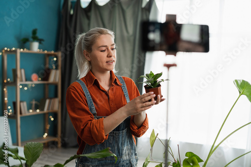Woman blogger is transplanting plant into new pot at home and recording video for her blog. Houseplant Care, repotting houseplants.