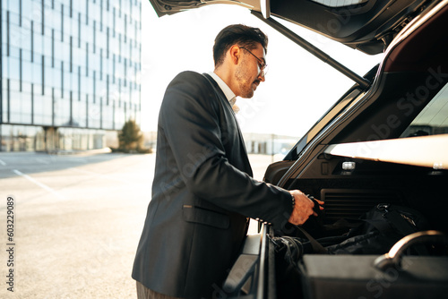 Successful businessman taking luggage from the car trunk