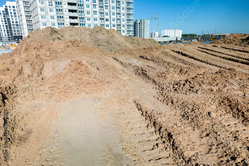 Open sand pit  for sand extraction during construction. The texture of sand and traces of the tread of large cars. Sand for construction work. Storage of sand at the construction site.