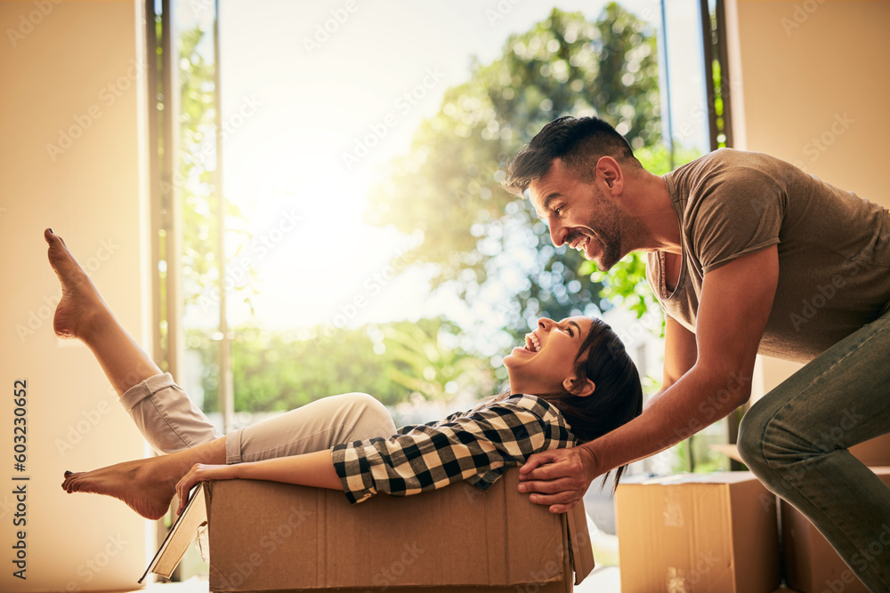 New house, funny and couple pushing box, having fun and bonding in apartment. Real estate, laughing and man and woman in cardboard, play and enjoying quality time together while moving into property. - obrazy, fototapety, plakaty 