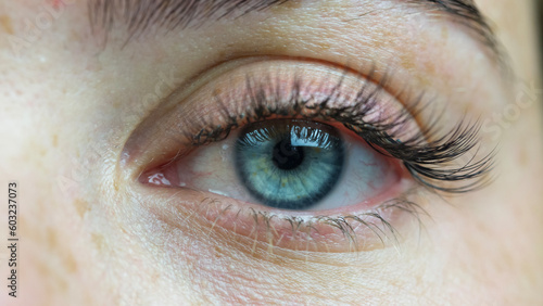 Close-up shot of a blue eye on the face of a beautiful girl with freckles