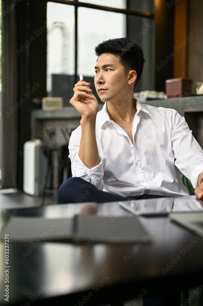 Focused Asian businessman planning his project while sitting in a coffee shop. Focused Asian businessman planning his project while sitting in a coffee shop.