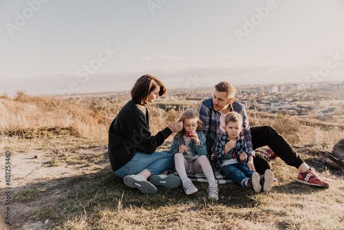 happy family spends time in nature. Son, daughter, dad and mom are hugging and laughing