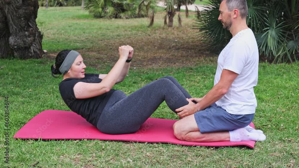 A couple practices outdor fitness on a mat in the park. Fitness workout outdoors. A couple practices outdor fitness on a mat in the park. Fitness workout outdoors.