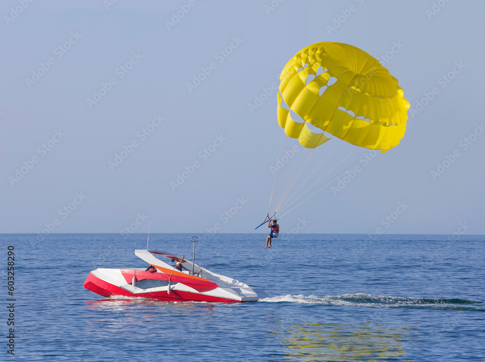A yellow parasail wing pulled by a powerboat. Guy takes a selfie A yellow parasail wing pulled by a powerboat. Guy takes a selfie