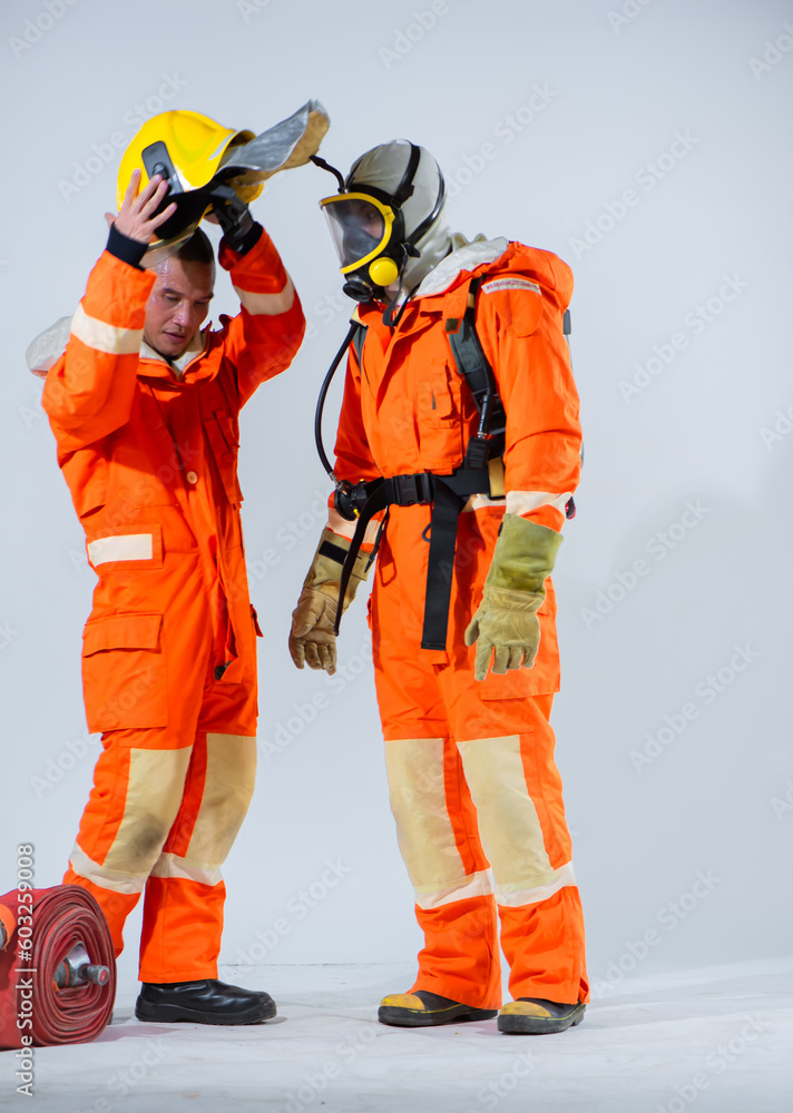 Against the clean white background the firefighter leans in with determination focused on removing the mask from their partner's face swiftly and safely. Against the clean white background the firefighter leans in with determination focused on removing the mask from their partner's face swiftly and safely.