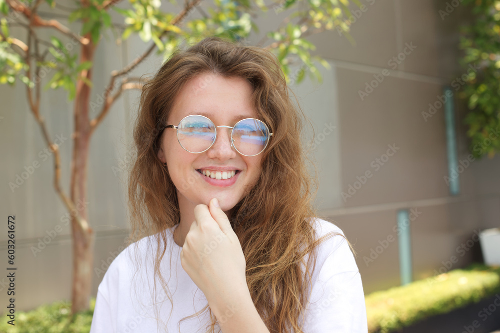 Portrait of happy beautiful young woman, teenager smile in glasses outdoors, walk at summer sunny day look at camera Portrait of happy beautiful young woman, teenager smile in glasses outdoors, walk at summer sunny day look at camera