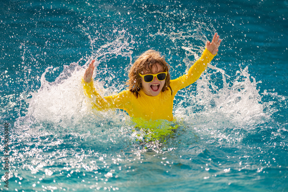 Excited kid enjoy summer holidays and summer vacation in swimming pool. Happy child playing in the sea or pool water. Healthy kids lifestyle. Cute child splash water at pool.