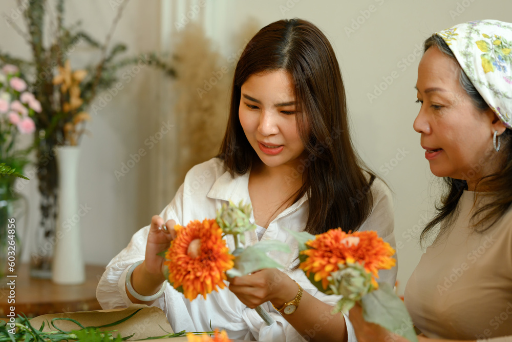 Asian senior woman and adult daughter making a bouquet with fresh flowers at floral shop
