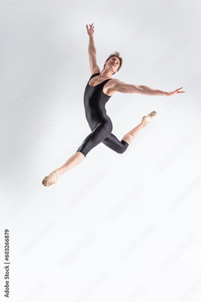Professional Ballet Dancer Young Caucasian Athletic Man in Black Suit Dancing in Studio On White Background With Lifted Hands.