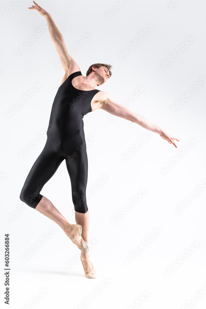 One Caucasian Ballet Dancer Young Athletic Man in Black Suit Posing in Stretching Pose Studio On White.
