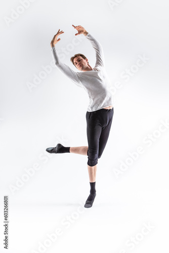 Fototapeta Naklejka Na Ścianę i Meble -  Caucasian Handsome Young Man Dancing Ballet Posing in Dancing Ballet Pose with Lifted Hands in White Shirt On White.