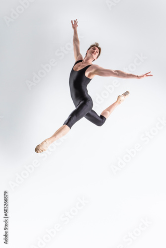 Professional Ballet Dancer Young Caucasian Athletic Man in Black Suit Dancing in Studio On White Background With Lifted Hands.