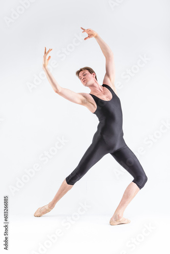 Professional Ballet Dancer Young Caucasian Athletic Man in Black Suit Posing Stretching in Studio On White With Lifted Hands. © danmorgan12