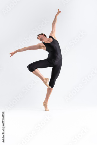 male Ballet Dancer Young Athletic Man in Black Suit Posing in Ballanced Stretching Dance Pose Studio On White.