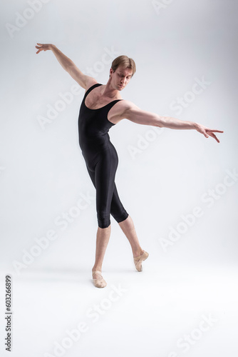 Sports Concepts. Athletic Caucasian Dancing Ballet Man Posing in Stretching Pose With Hands Lifted in Line in Black Tights On White