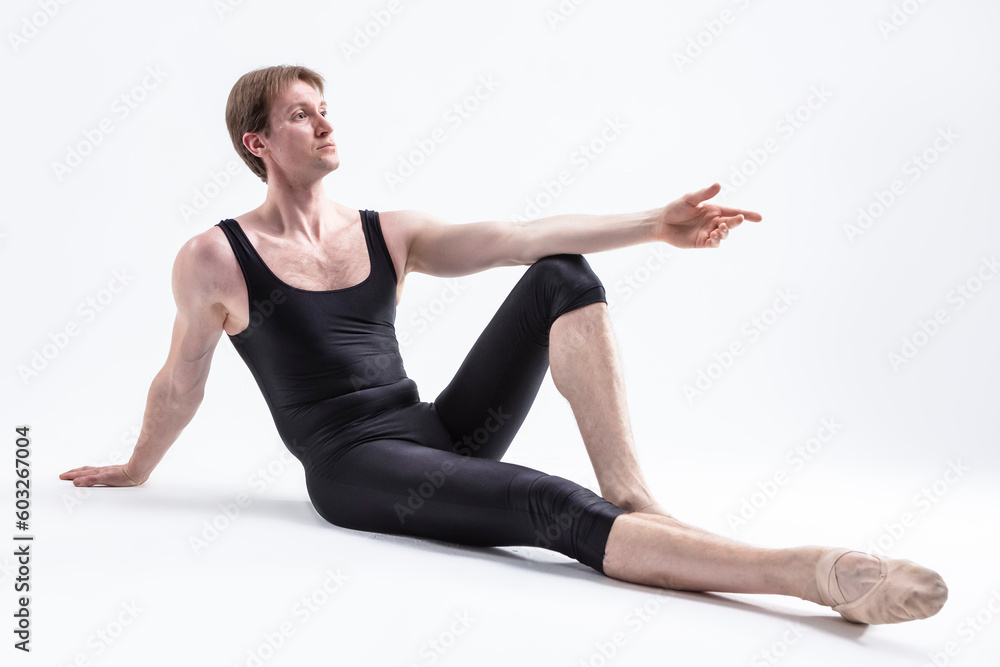 Relaxed Ballerino Dancer Sitting While Practising Stretching Exercices Before Training In Black Sportive Tights in Studio.