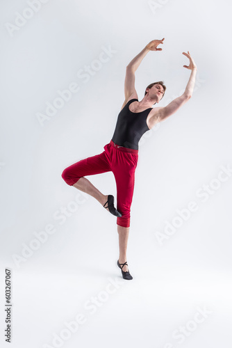 Ballet Ideas. Modern Ballet of Flexible Athletic Man Posing in Red Tights in Ballanced Dance Pose With Hands Lifted in Studio on White.