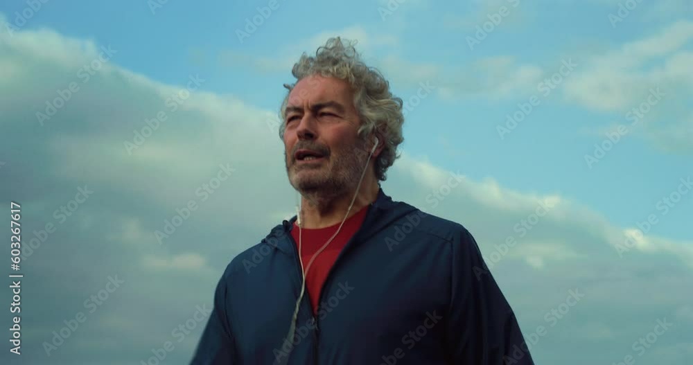 Portrait of a Motivated Middle-Aged Man in Sports Clothes Training and Jogging While Having a Call Using Earpods. Businessman Staying Fit and Working Out During his Retreat Weekend in Countryside Portrait of a Motivated Middle-Aged Man in Sports Clothes Training and Jogging While Having a Call Using Earpods. Businessman Staying Fit and Working Out During his Retreat Weekend in Countryside