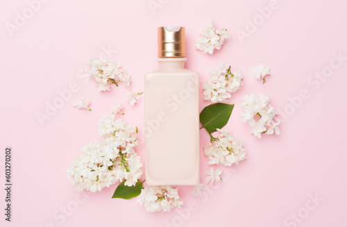 Composition with cosmetic bottle and flowers on color background, top view