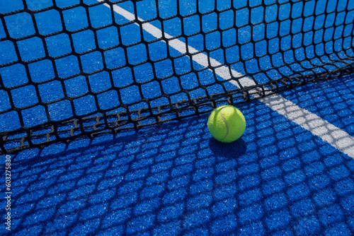 ball in the shade of the net of a paddle tennis court, racket sports concept © Vic