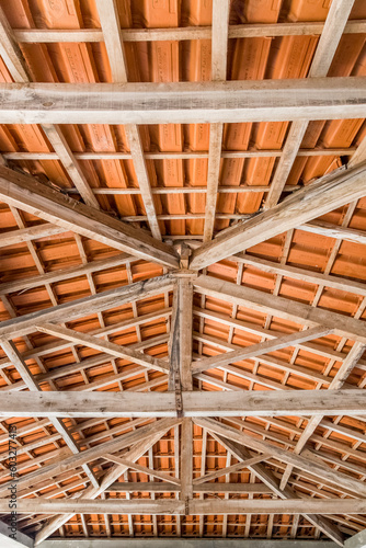 Roof seen from the inside from the bottom up with a wooden structure and orange tiles. Abstract and symmetric image.