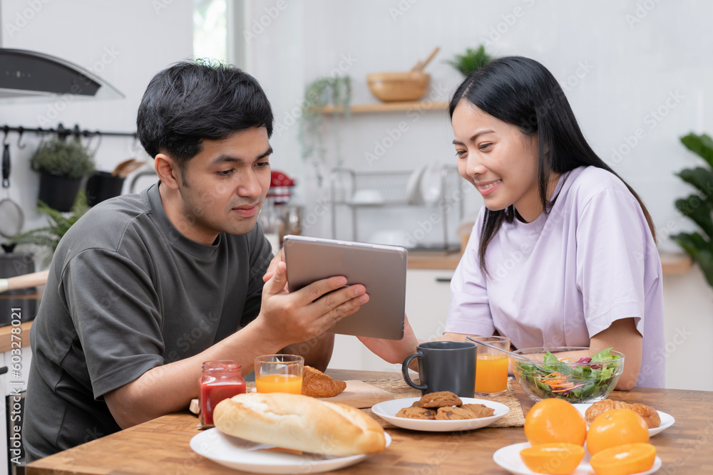 Asian couple smiling and happily use smartphone to online shopping. Husband ready to pay birthday present for beautiful wife. Find accommodation online for honeymoon, App online, book flight tickets. Asian couple smiling and happily use smartphone to online shopping. Husband ready to pay birthday present for beautiful wife. Find accommodation online for honeymoon, App online, book flight tickets.