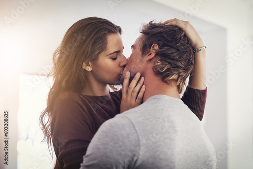 Couple, love and kissing in home for romantic bond, quality time and care together. Young man, woman and kiss for romance of lovers in happy relationship, intimate moment and passionate affection photo