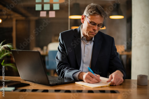 Businessman working with laptop at office. Businessman sitting at office desk working on laptop computer..