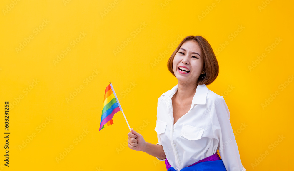 Portrait of Asian woman waving LGBTQ rainbow flag for coming out of the closet in pride month to promote marriage equality and differences of homosexual and discrimination Portrait of Asian woman waving LGBTQ rainbow flag for coming out of the closet in pride month to promote marriage equality and differences of homosexual and discrimination