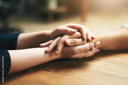Holding hands, comfort and support of friends, care and empathy together on table in home mockup. Kindness, love and women hold hand for hope, trust or prayer, solidarity or compassion, help or unity