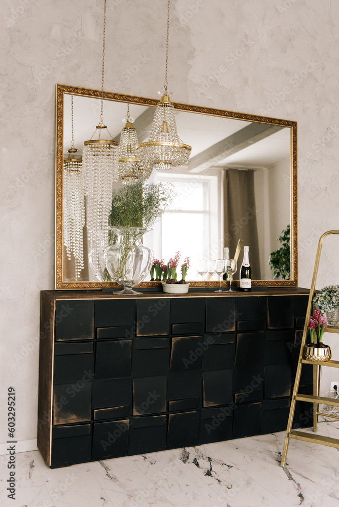 Stylish interior design with a large mirror, crystal gold chandeliers and dressers, luxurious interior