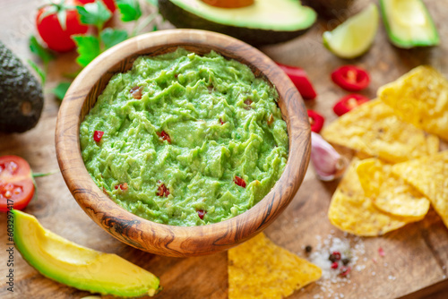 Guacamole, guacamole ingredients and chips on wooden background.  Flat lay.