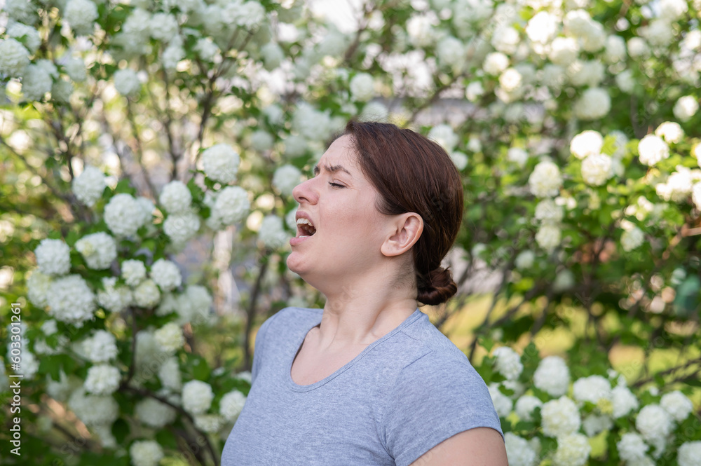 Caucasian woman suffers from allergies and sneezes while walking in the park. Caucasian woman suffers from allergies and sneezes while walking in the park.