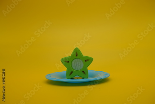 toy starfruit and blue plate isolated on yellow background. Star fruit toys that can be attached and removed.