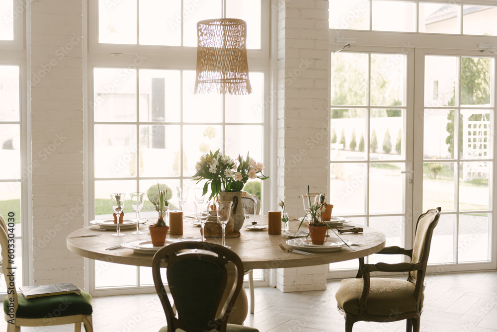 Dining table with vintage chairs with beautiful setting, glasses and fresh flowers