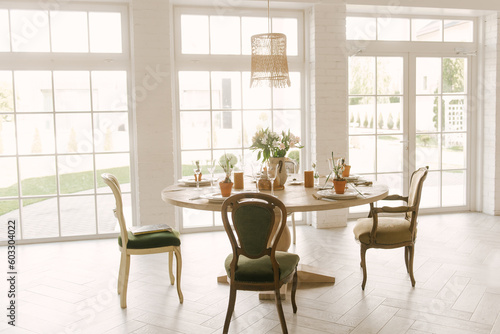 Dining table with vintage chairs with beautiful setting  glasses and fresh flowers