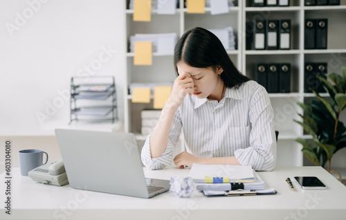 Asian business woman is stressed, bored, and overthinking from working on a tablet at the modern office.