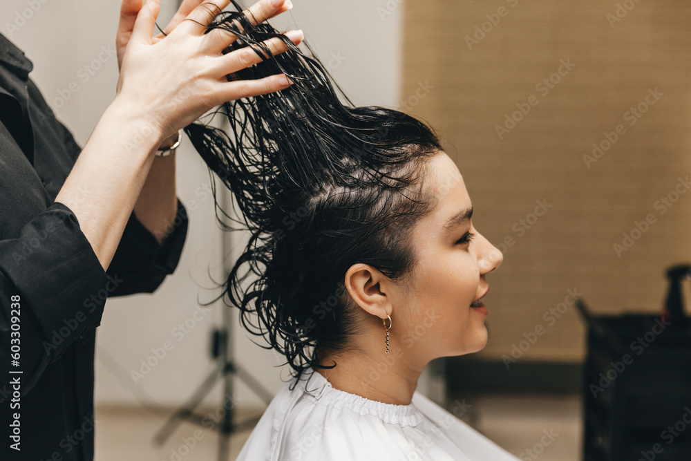 Fototapeta premium The hairdresser applies the gel on the hair of a woman in a beauty salon.