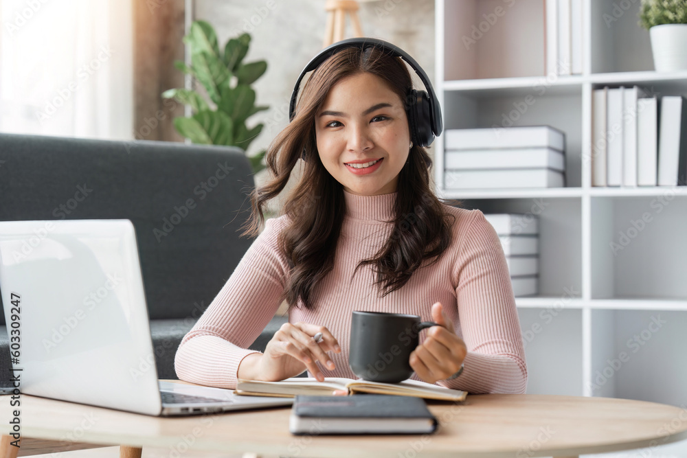 Beautiful asian woman relaxing using laptop computer while sitting on table with coffee, concept at home Beautiful asian woman relaxing using laptop computer while sitting on table with coffee, concept at home
