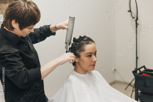 Close-up of the hands of a hairdresser drying women's hair with a hairdryer. short haircut and styling