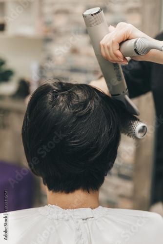 Close-up of the hands of a hairdresser drying women's hair with a hairdryer. short haircut and styling