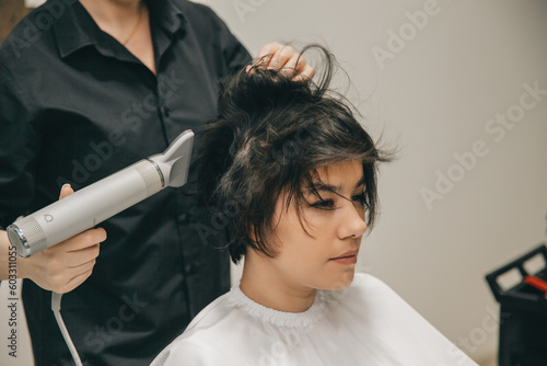 Close-up of the hands of a hairdresser drying women's hair with a hairdryer. short haircut and styling