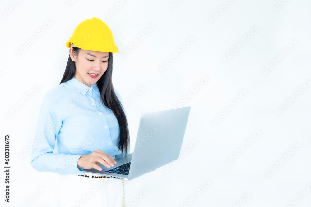 Asian woman architect or construction engineer wear yellow hardhat on white background.Young asian architect woman smiling happy. Asian woman architect using laptop. Construction, Industry concept.