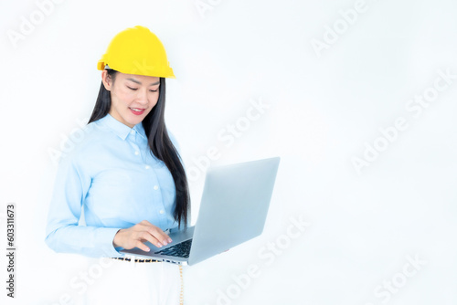 Asian woman architect or construction engineer wear yellow hardhat on white background.Young asian architect woman smiling happy. Asian woman architect using laptop. Construction  Industry concept.