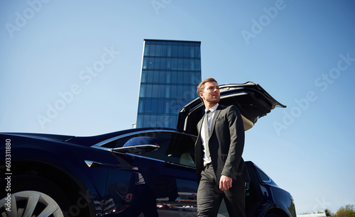 View from below. Doors are opened. Businessman is standing near his car outdoors © standret